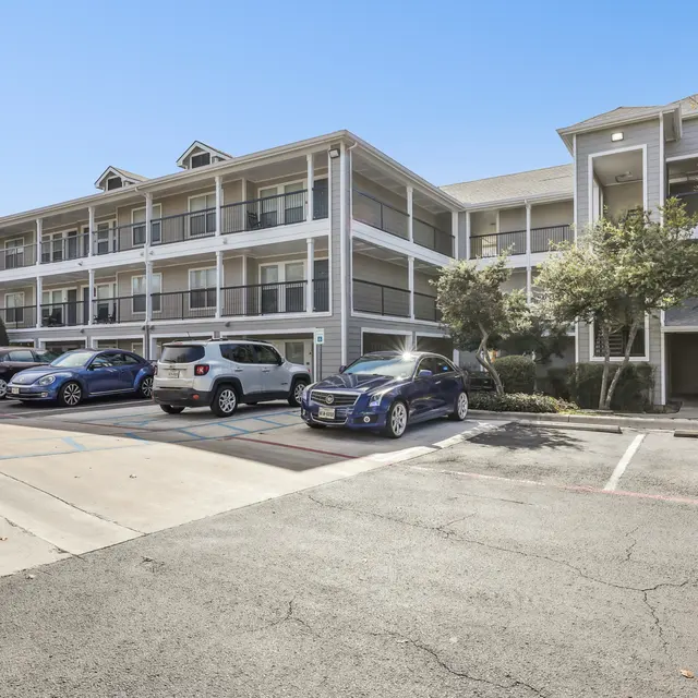 A parking lot with cars and a building in the background.